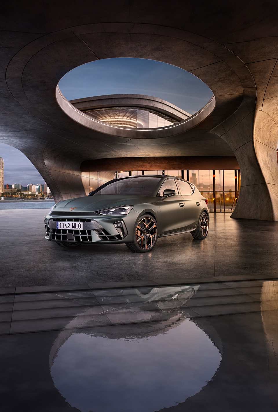 three quarter front view of new cupra Leon 2024 in Enceladus grey and architectural structure, parked on smooth cement, backdrop of Barcelona cityscape.